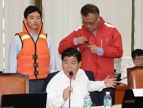 새누리당 이이재 의원이 11일 국회 농림축산식품해양수산위원회에서 열린 해양수산부 등 국정감사에서 GPS와 발열장치를 갖추고 착용감을 개선한 신형 기능성 구명조끼(오른쪽)와 현재 사용되고 있는 구명조끼를 비교해 보여주고 있다.(사진=연합뉴스)