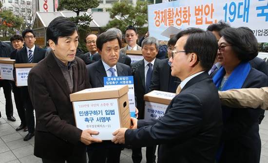 전경련을 비롯한 경제단체 대표들이 지난 2월 22일 서울 여의도 더불어민주당 당사 입구에서 당 관계자들에게 ‘경제활성화 법안 입법 촉구 서명부’를 전달하고 있다. 어버이연합이 전경련의 뒷돈을 받고 동원됐다는 의혹이 제기되면서 서명운동 자체의 도덕성이 훼손되고 있다. (사진=연합뉴스)