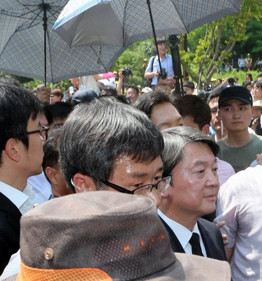 고(故) 노무현 전 대통령 서거 7주기 추도식이 열린 23일 경남 김해 봉하마을에서 국민의당 안철수 공동대표가 경찰의 경호를 받으며 걷고 있다. 곳곳에서 안 대표를 향한 야유와 욕설이 쏟아지는 가운데 혹시 모를 ‘물 세례’를 막기 위해 경호팀이 우산을 펼쳐들고 있다. (사진=연합뉴스)