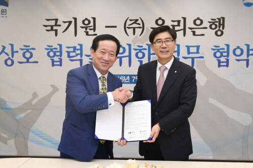 지난 27일 우리은행 본점에서 이광구 은행장(사진 오른쪽)이 오현득 국기원장(왼쪽)과 함께 ‘우리은행·국기원, 상호협력을 위한 포괄적 업무협약’을 체결하고 있다. (사진=우리은행)