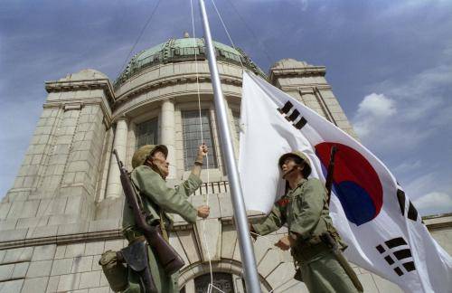 보훈처는 한국전쟁 중 ‘9.28 서울 수복’ 때 중앙청에 태극기를 게양한 역사성을 감안해 당시 중앙청 자리(현 광화문)와 가장 가까운 광화문 광장에 태극기를 상시 게양하자고 서울시에 요구하고 있다. 사진은 1993년 9월 28일 서울수복 기념행사에서 6.25 참전용사들이 중앙청 태극기 게양을 재현하고 있다. (사진=문화체육관광부 e영상역사관)
