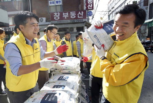 대림산업 김한기 사장(우측)이 사랑의 쌀 배달을 위해 쌀을 짊어지고 있다. (사진=대림산업)