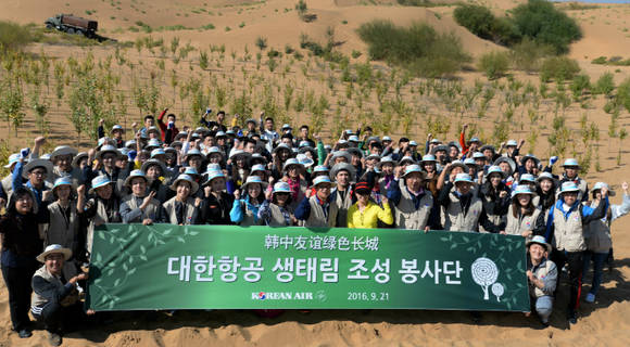 중국 네이멍구(內蒙古) 쿠부치 사막에서 나무심기 봉사활동에 참가한 대한항공 직원들과 중국 대학생들이 기념 촬영을 하고 있는 모습. (사진=대한항공)