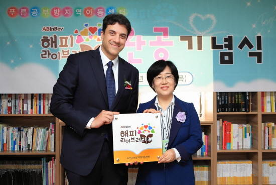 지난 3일 오후 서울 영등포구 ‘푸른공부방지역아동센터’에서 열린 오비맥주 ‘해피 라이브러리’ 1호 완공 기념식에서 오비맥주 김도훈 사장 (왼쪽)과 푸른공부방 지역아동센터 이정순 센터장이 현판식에 앞서 기념 촬영을 하고 있다. (사진=오비맥주)