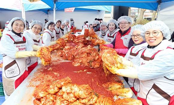 BNK경남은행 손교덕 은행장(사진 오른쪽 세번째)과 부인 송혜경 여사(사진 오른쪽 네번째)가 7일 '2016 사랑의 김장 나눔 대축제' 에 참여해 자원봉사자들과 함께 김장을 담그고 있다. (사진제공=경남은행)
