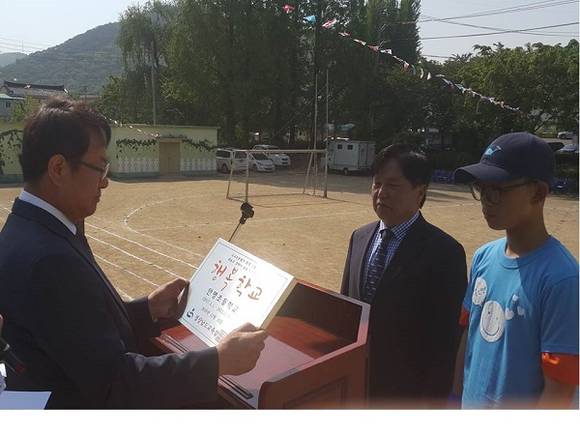 신용진 김해교육장이 이수광 안명초 교장에게 행복학교 현판을 전달하고 있다. (사진제공=김해교육지원청)