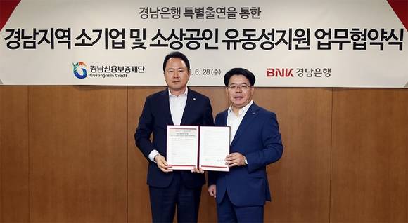 BNK경남은행 손교덕 은행장(사진 오른쪽)이 경남신용보증재단 이광시 이사장과 '경남지역 소기업 및 소상공인 유동성 지원 업무 협약' 을 체결한 후 기념촬영하고 있다. (사진제공=경남은행)