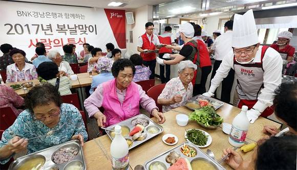 12일 BNK경남은행 손교덕 은행장과 BNK경남은행 임원부인회봉사단원들이 의창복지회관을 찾은 노인과 장애인들에게 사랑의 특식을 배식하고 있다. (사진제공=BNK경남은행)