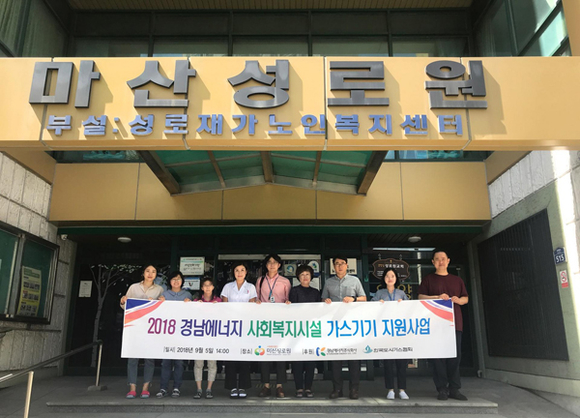 경남에너지가 5일 가스기기 및 기기 설치를 위한 배관공사비를 무상으로 지원하고 관계자들이 마산성로원 앞에서 기념촬영을 하고 있다. (사진제공=경남에너지)
