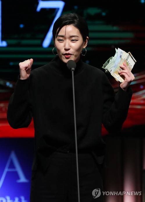 트로피를 판매하고 받은 현금 50만 원을 들고 기뻐하는 가수 이랑.(사진=연합뉴스)