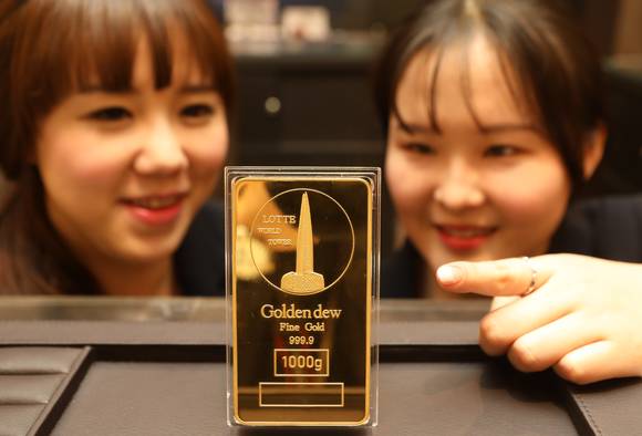롯데백화점 모델 2명이 롯데월드타워 이미지가 새겨진 골드바를 보는 모습. (사진=롯데백화점)