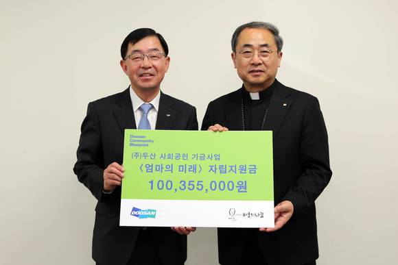 박완석 ㈜두산 부사장(왼쪽)이 재단법인 바보의나눔 손희송 이사장에게 미혼모 자립지원금을 전달하고 있다. (사진=(주)두산)