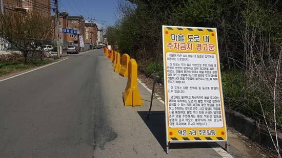 덕은리 주민들이 무단주차를 막기 위한 설치물과 안내문이 즐비하다. 이 도로에서 교통사고로 1명이 사망했다. (사진= 김진부 기자)