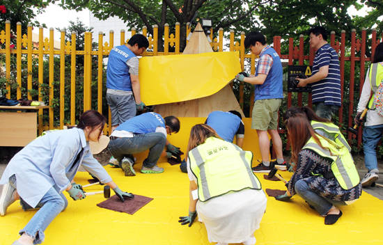 지난 9일 삼성전자 임직원 봉사자와 용인초등학교 학부모들이 아이들의 안전한 통학을 위해 학교 인근 횡단보도 앞에 '옐로카펫'을 설치하고 있다. (사진=삼성전자)