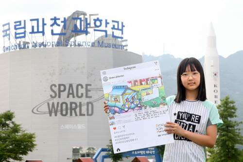 대상에 선정된 신지민 양(11세)이 ‘제2회 브릴리언트 키즈 모터쇼’가 열릴 국립과천과학관에서 ‘백과사전 자동차’ 그림 작품을 들고 있는 모습. (사진=현대자동차)