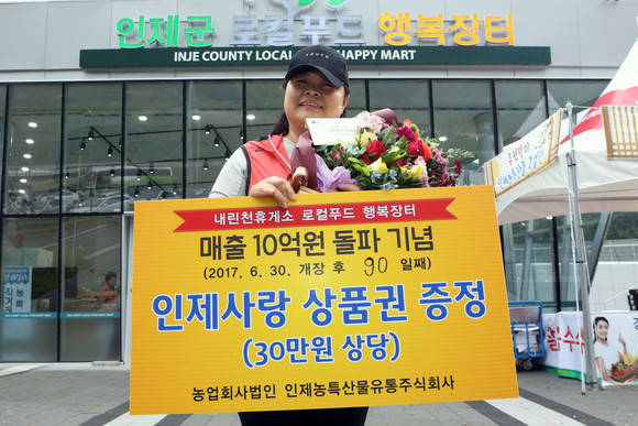 10억 매출 달성 시점 구매 고객이 꽃다발과 인제사랑상품권을 받고 기뻐하고 있다 ㅣ 사진=인제군 제공