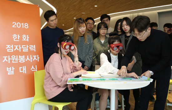 2018 한화 점자달력 봉사단 발대식 및 오리엔테이션에 참가한 자원봉사자들이 점자달력 제작에 앞서 저시력 시뮬레이터를 활용해 시각장애를 직접 체험해보고 있다.(사진=한화그룹)