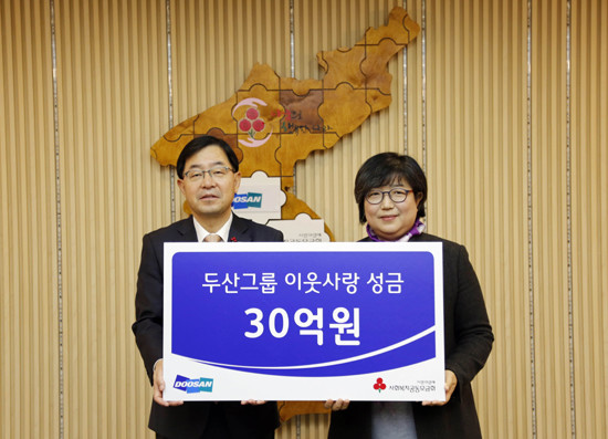 박완석 ㈜두산 부사장(왼쪽)이 김연순 사회복지공동모금회 사무총장에게 성금을 전달하고 있다. (사진=두산 제공)