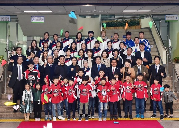 염태영 수원시장(2번째 줄 오른쪽 5번째), 새라 머레이 국가대표 여자 아이스하키팀 감독(염 시장 왼쪽)과 선수들, 수원시 아이스하키 유소년팀 선수들이 기념촬영을 하고 있다.(사진=수원시)