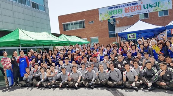 봄김치 이웃 나눔 행사에 참여한 자원봉사자들이 기념촬영을 하고 있다.(사진=수원시)