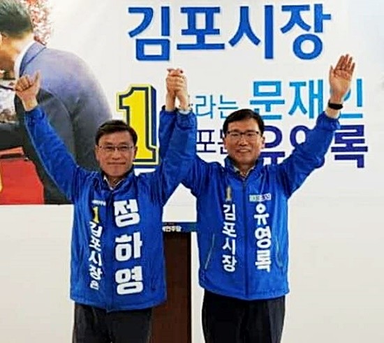 민주당 김포시장 후보로 결정된 정하영(좌측)이 공천에서 배제된 유영록 김포시장과 손을 맞잡고 있다(사진= 정하영 캠프)