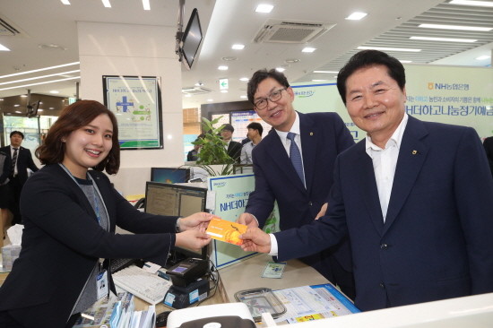 김병원 농협중앙회장이 27일 본점 영업부를 방문해 1호 고객으로 상품에 가입 후 이대훈 NH농협은행장, 영업점직원과 함께 기념촬영을 하고 있다. (왼쪽부터 김부경 계장, 이대훈농협은행장, 김병원 농협중앙회장). (사진=농협은행)