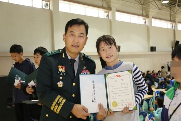 3일, 육군 51사단에서 진행된 호국문예행사‘호국 글짓기 및 그림그리기 대회’에서 창의상을 수상한 광일초등학교 5학년 유은서 학생과 김인건(소장) 사단장이 기념 사진촬영을 하고 있다.(사진=51보병사단)