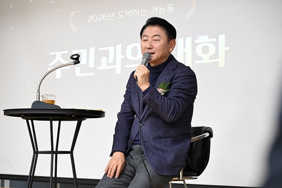 의정부시 가능동주민센터 3층 가능홀에서 주민과 내빈이 참석한 가운데 2026년 주요업무보고회가 열리고, 무대에서 사업 계획을 설명하는 모습
